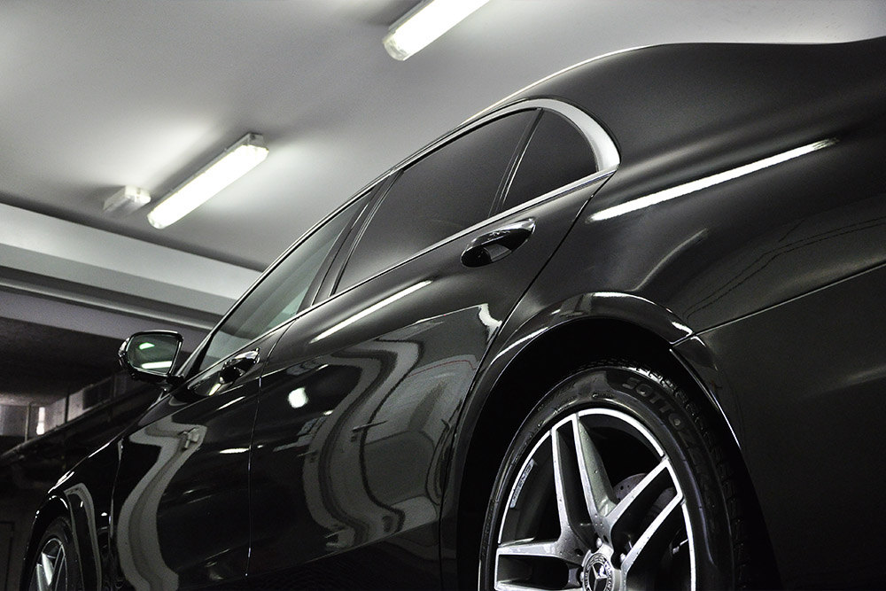 Photo of a side of a black sedan car treated with Soft99 Rain Drop car care product. Highly glossy paintwork is visible on the car.